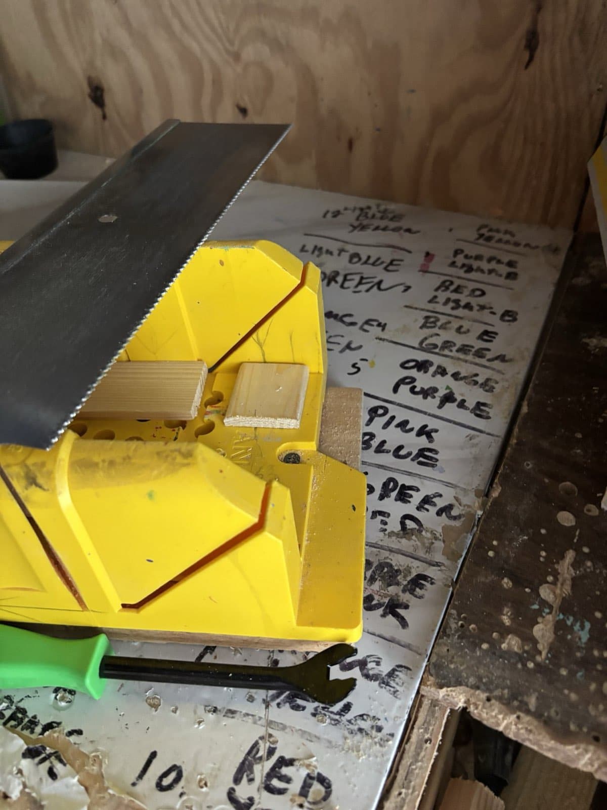 Paul Allabaugh's workshop whiteboard with a saw resting against it and a Rainbow Bridge order written out by hand